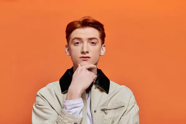 Young man shows emotion in a thoughtful pose against a striking orange backdrop. — Stock Photo