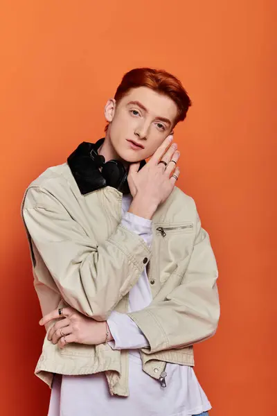 A handsome young man expresses deep emotions while standing in front of a bright orange background. — Stock Photo