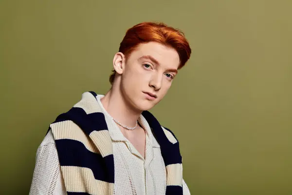 Un beau jeune homme aux cheveux roux montre des émotions profondes dans un contexte vert calme. — Stock Photo
