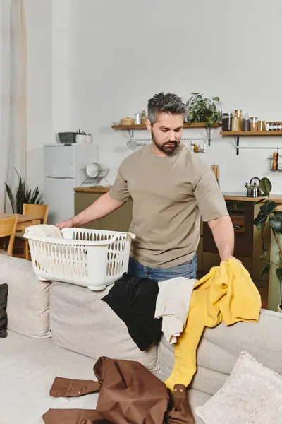 Ein Mann sortiert frisch geputzte Wäsche in einem gemütlichen Heim, umgeben von einem warmen, einladenden Dekor. — Stockfoto