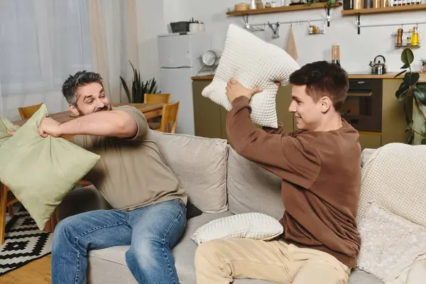 Two brothers engage in a playful pillow fight, creating a lively and cheerful atmosphere at home. — Stock Photo