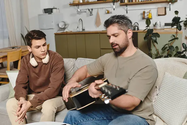 Two brothers enjoy a warm afternoon at home while learning guitar together in a cozy space. — Stock Photo