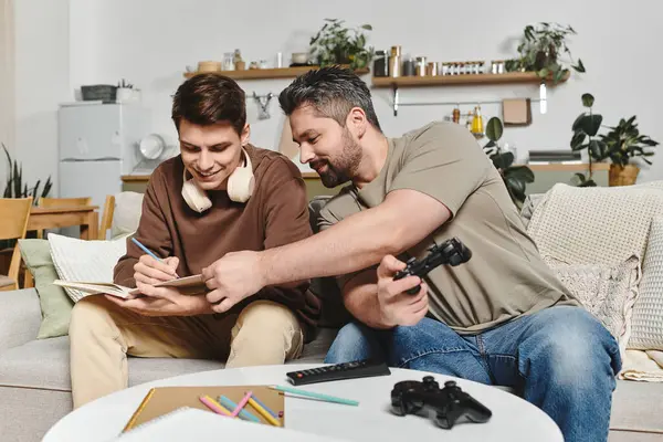 Due fratelli godono di un pomeriggio a casa, uno scrive mentre l'altro si impegna nel gioco. — Foto stock