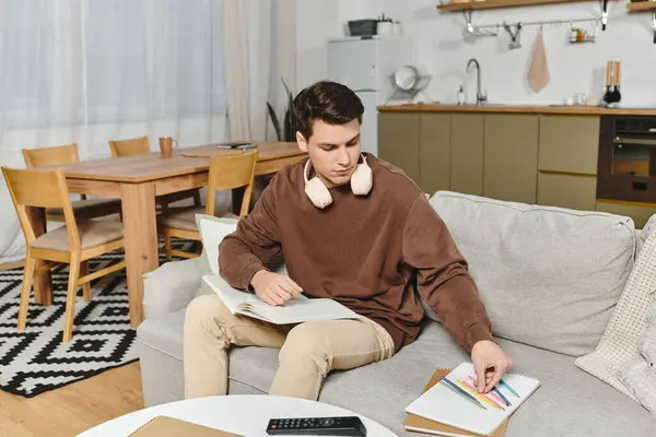 A young man enjoys a peaceful afternoon at home, engaged in reading and creativity. — Stock Photo