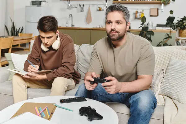 Two brothers enjoy time together, one playing a video game while the other sketches ideas. — Stock Photo