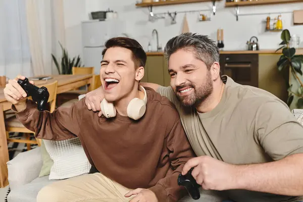Two brothers share laughter and excitement while playing video games in a comfy home setting. — Stock Photo