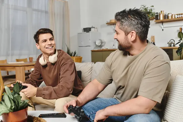 Two brothers are having fun playing video games and laughing together at home. — Stock Photo