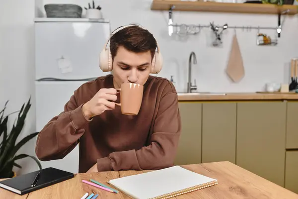 Sipping tea while immersed in calm music, creating a peaceful atmosphere in a homely kitchen. — Stock Photo