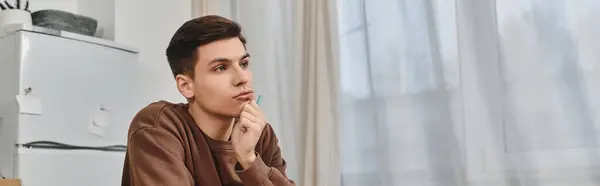 A young man reflects quietly, immersed in thoughts within a cozy home setting. — Stock Photo
