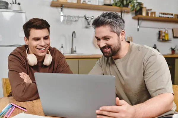 Dos hermanos se dedican a una animada discusión mientras trabajan juntos en un portátil en casa. - foto de stock