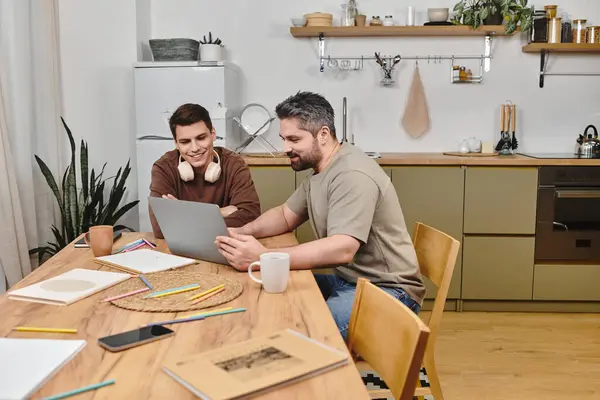 Two brothers engage in an enriching experience, sharing ideas over a laptop in a cozy kitchen. — Stock Photo