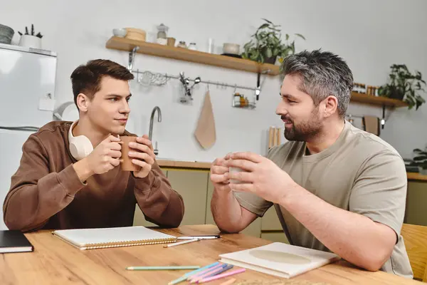 Two brothers share meaningful stories at a cozy kitchen table, illuminated by warm, natural light. — Stock Photo