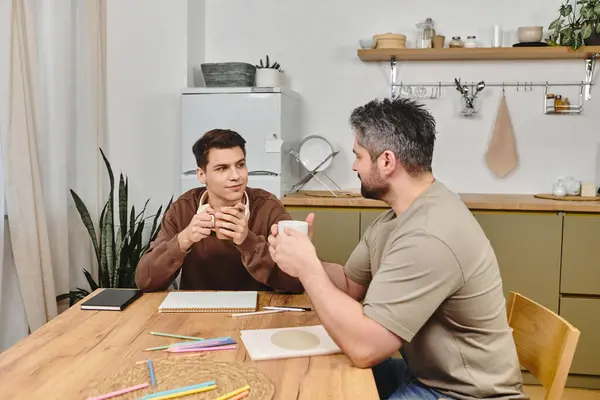 Dois irmãos se envolvem em uma discussão sincera enquanto desfrutam de café em uma mesa de cozinha acolhedora. — Fotografia de Stock
