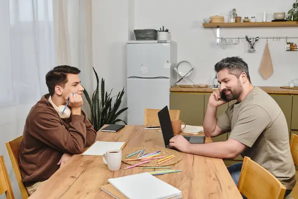 Two brothers engage in a friendly conversation at a wooden table, enjoying their time together. — Stock Photo