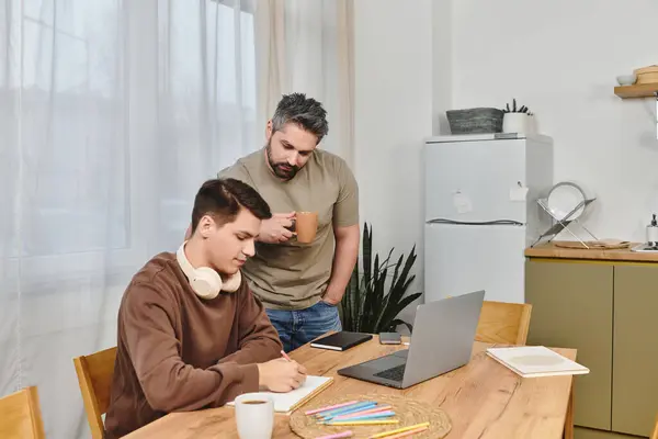 A young man writes creatively at home with support and encouragement from his brother. — Stock Photo