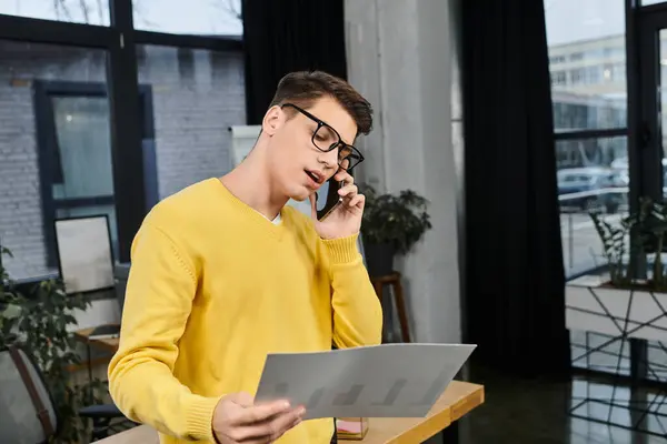 A young professional joins onboarding while talking on the phone and reviewing documents. — Stock Photo