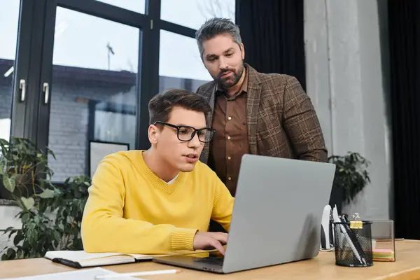 A new employee engages with a laptop while receiving guidance from a mentor in the office. — Stock Photo