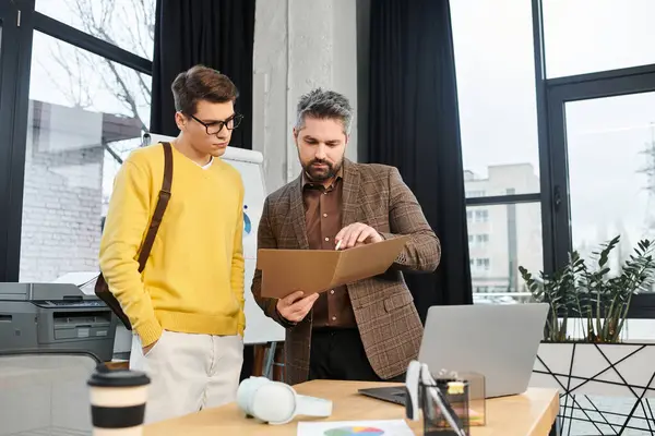 Un mentor ayuda a un nuevo miembro del equipo a revisar documentos importantes en el trabajo en su primer día. - foto de stock