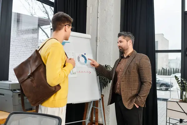 A newcomer engages with a mentor while reviewing onboarding materials in a stylish office. — Stock Photo