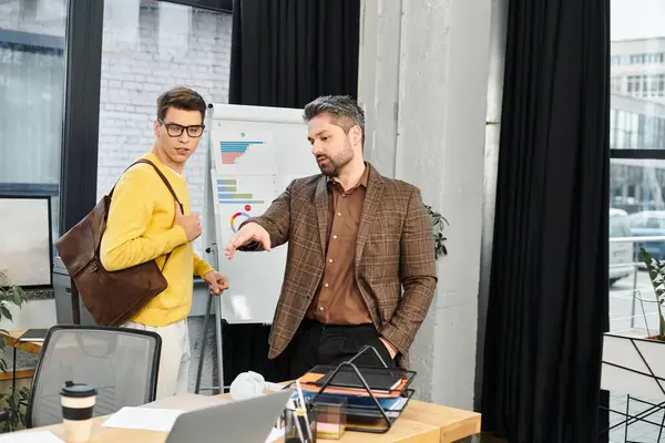 Un nuevo empleado recibe orientación y consejos de un mentor en un espacio de oficina brillante y contemporáneo. - foto de stock