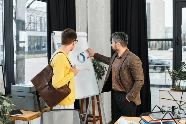 A gentleman in formal attire explains a chart to a new employee on his first day at work. — Stock Photo