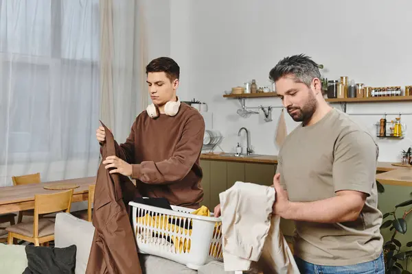 Zwei Brüder falten fröhlich Wäsche zu Hause, während sie sich in gemütlicher Gesellschaft gegenseitig genießen. — Stockfoto