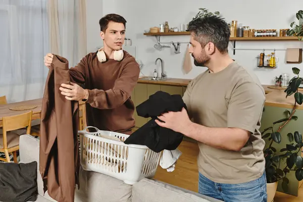 Zwei Brüder falten gemeinsam Wäsche in ihrem einladenden Zuhause und genießen einen gemütlichen Moment zusammen. — Stockfoto