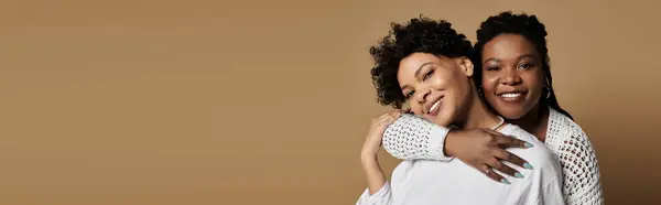 Two fashionable women showcase their love in a vibrant, stylish setting with cheerful expressions. — Stock Photo