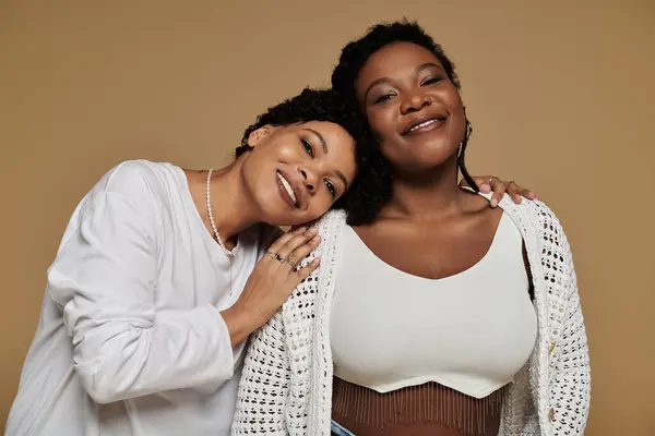 Two stylish women share a tender moment, showcasing their chic outfits and radiant smiles. — Stock Photo