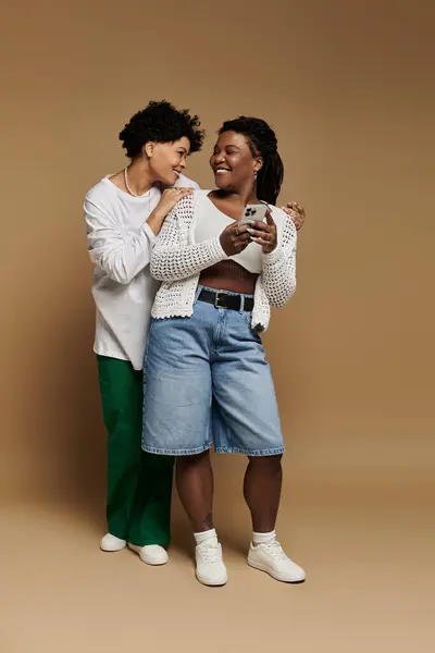 A stylish lesbian couple shares a joyful moment, smiling at each other while dressed trendy. — Stock Photo
