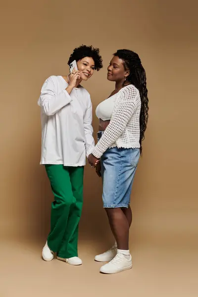 Two fashionable women smile at each other while holding hands and enjoying their time together — Stock Photo