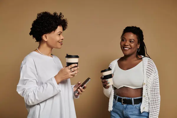 Zwei modische Frauen genießen gemeinsam Kaffee, strahlen Liebe und Freude in einer lebendigen Atmosphäre aus. — Stockfoto