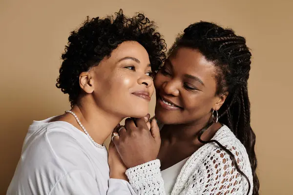 Dos mujeres elegantes abrazan cariñosamente, exudando amor y calidez en un ambiente acogedor. - foto de stock