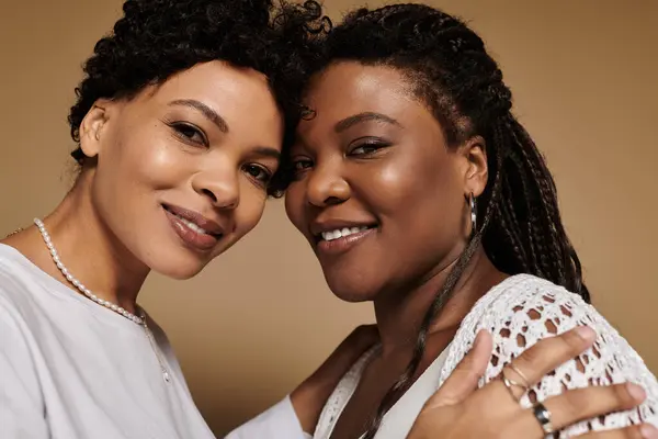 Two stylish women embrace, showcasing their trendy outfits and bright smiles. — Stock Photo