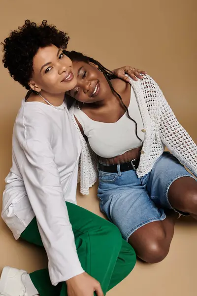 Two stylish women share a loving moment, highlighting their vibrant personalities. — Stock Photo