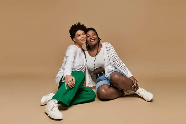 Two beautiful women in trendy outfits radiate love and happiness while posing playfully together. — Stock Photo
