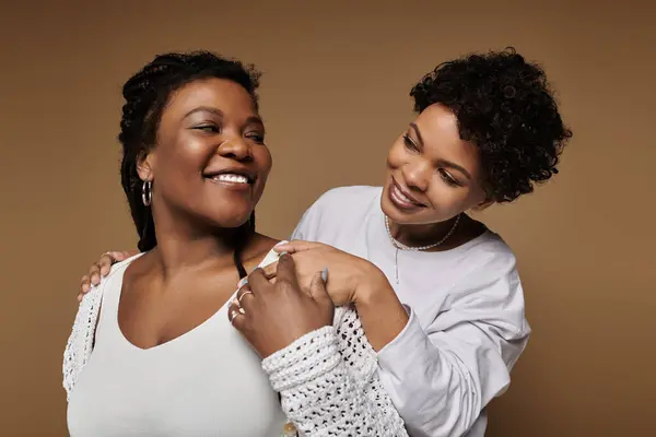 Two beautiful women dressed in fashionable attire celebrate their love in a chic studio. — Stock Photo