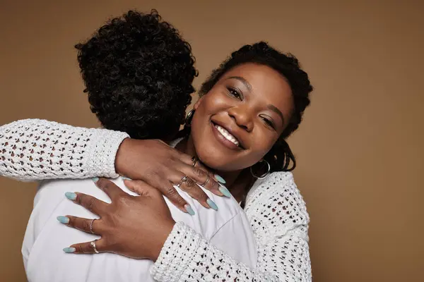 Two fashionable women share a warm embrace, radiating love and happiness in a chic atmosphere. — Stock Photo