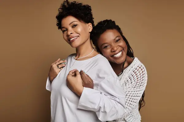 Two fashionable women embrace each other happily, showcasing their vibrant and stylish outfits. — Stock Photo