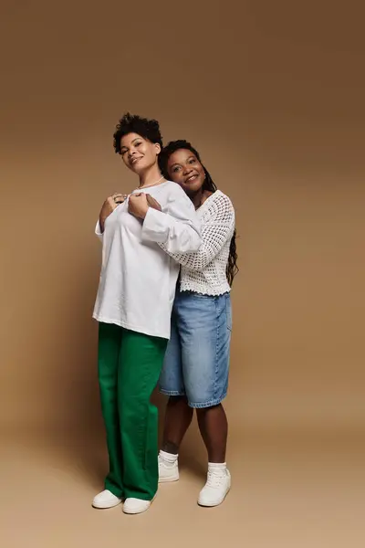 Stylish couple embraces each other, radiating joy and confidence in a warm, trendy space. — Stock Photo