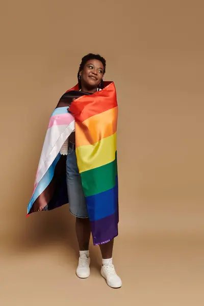 Stylish individual wrapped in a rainbow flag, radiating joy and confidence. — Stock Photo