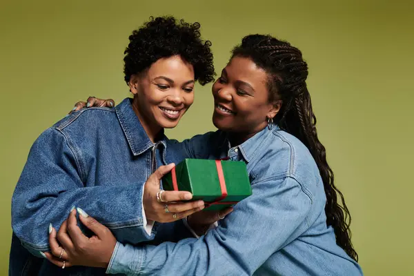 A loving couple in trendy outfits enjoys a heartfelt moment as they unwrap a gift, radiating joy. — Stock Photo