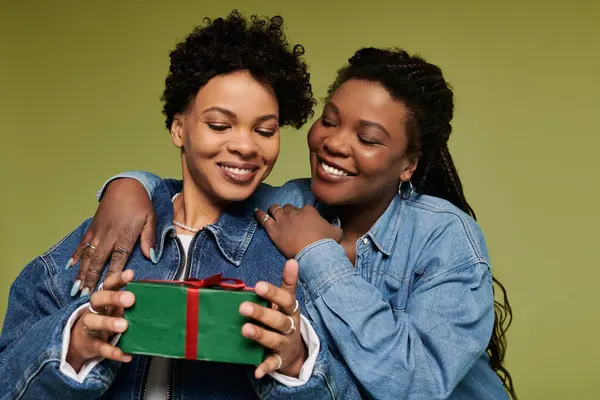 A fashionable lesbian couple exchanges a heartfelt gift, showcasing their love and vibrant styles. — Stock Photo