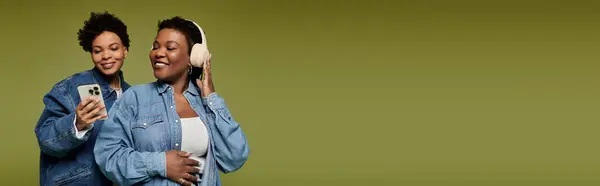 Zwei stilvolle Frauen teilen einen freudigen Moment, lächeln und genießen gemeinsam Musik. — Stockfoto