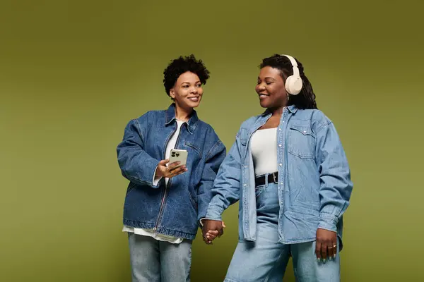 Two fashionable women share a loving moment, showcasing their stylish denim attire with joy. — Stock Photo