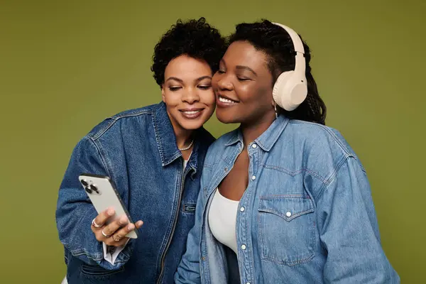 Two stylish women enjoy a playful moment, sharing a laugh as they capture a selfie on their phone. — Stock Photo