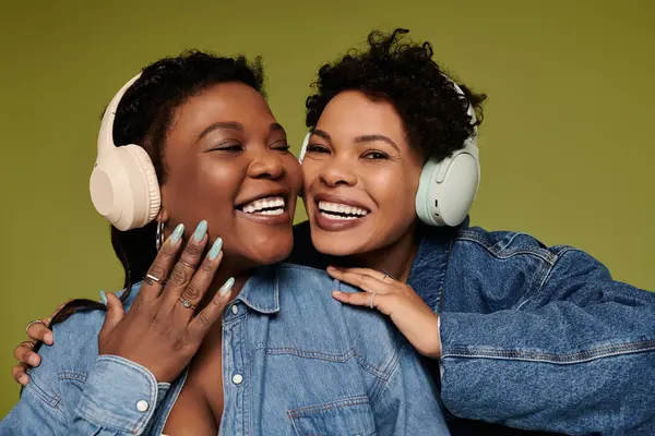 A joyful couple in trendy denim jackets and headphones radiates happiness. — Stock Photo