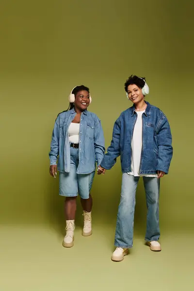 Two fashionable women enjoy each others company while wearing trendy attire and headphones. — Stock Photo