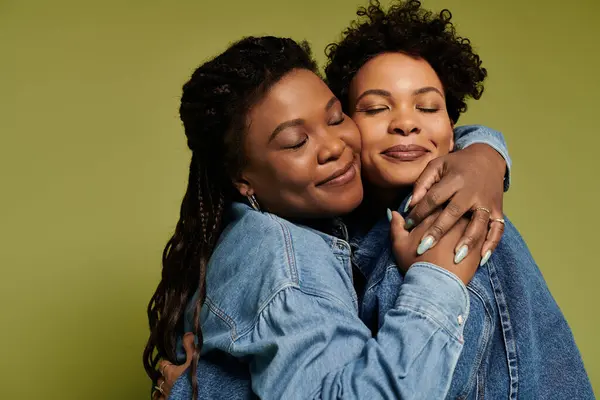 Two fashionable women share a warm hug, radiating love and joy, dressed in trendy denim jackets. — Stock Photo