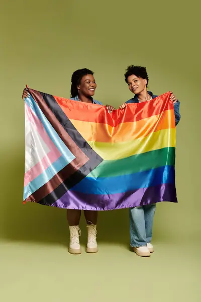 Charming couple smiles as they showcase a colorful pride flag, celebrating love and unity. — Stock Photo